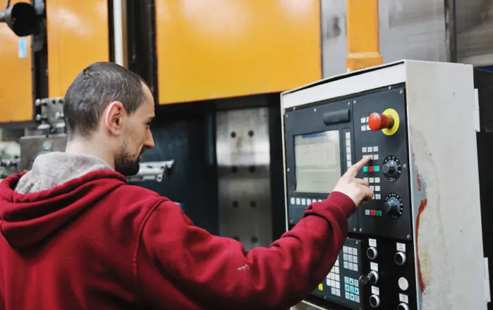 Machine operator using the control panel of industrial manufacturing equipment